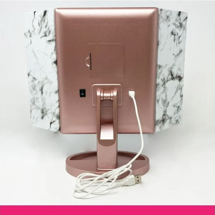 Back view of a rose gold trifold makeup mirror with a white USB cord.