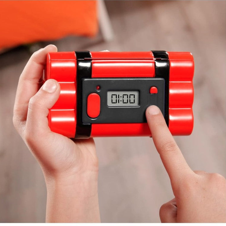 A person holding a red toy dynamite stick with a digital timer.