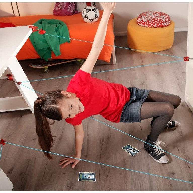 Young girl playing with a laser maze in a bedroom, wearing a red shirt, jean shorts, and black tights.