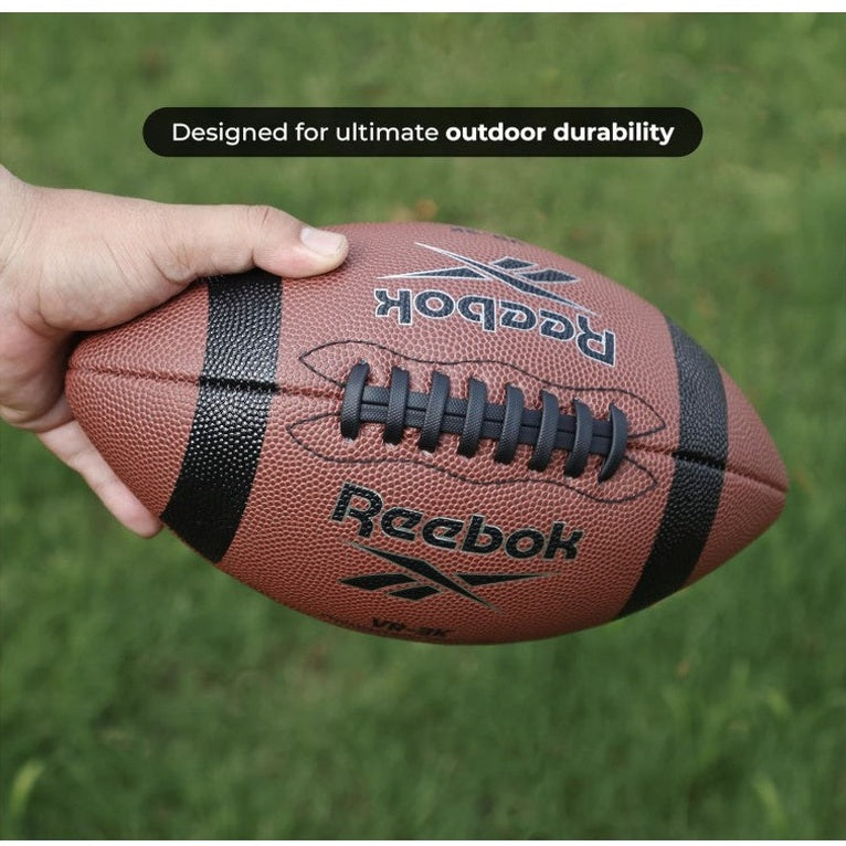 Close-up of a brown Reebok football held by a hand, with the text "Designed for ultimate outdoor durability" in the background.