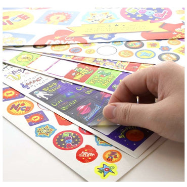 A hand peeling a sticker from a sheet of colorful reward stickers.