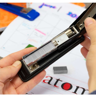 A black stapler held open, loaded with staples.