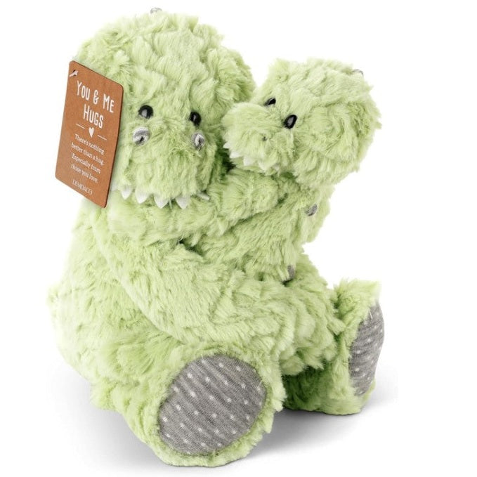 Two light green fuzzy dinosaur stuffed animals hugging each other with a brown tag that reads "YOU & ME HUGS".
