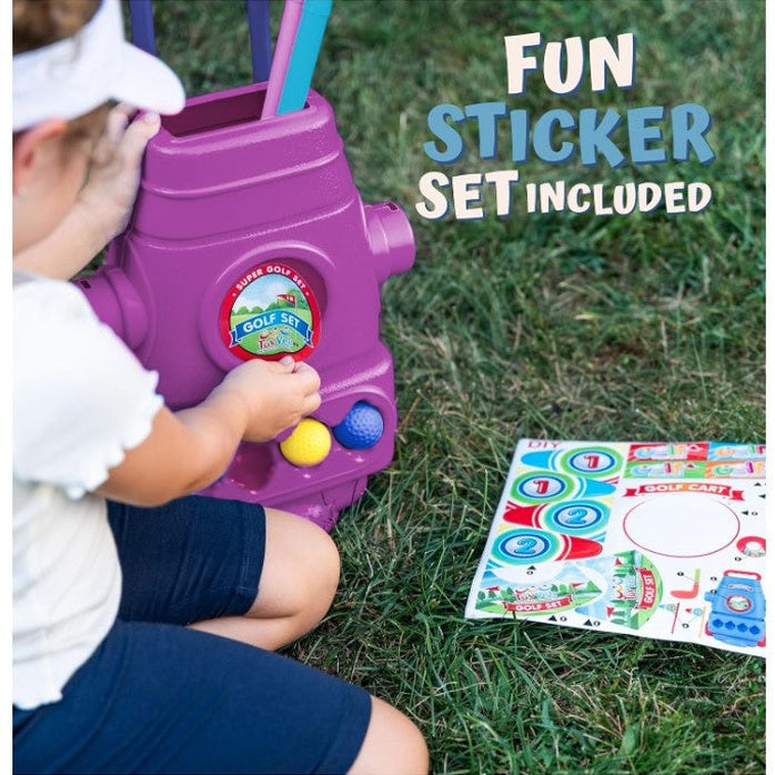 A child kneels on grass next to a purple toy golf cart and sticker set.