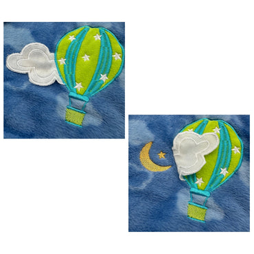 Close-up of blue fabric with embroidered hot air balloon, cloud, moon, and stars.