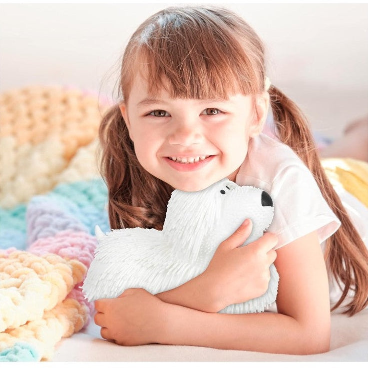 Smiling girl holding a white plush toy dog.