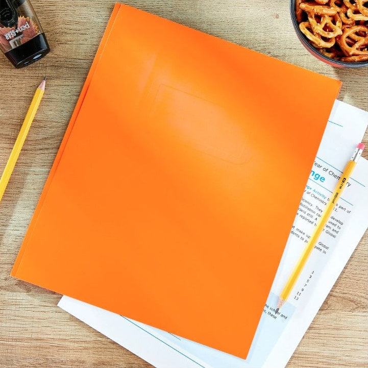Orange folder on a wooden desk, with papers, pencils, a pencil sharpener, and a bowl of pretzels.