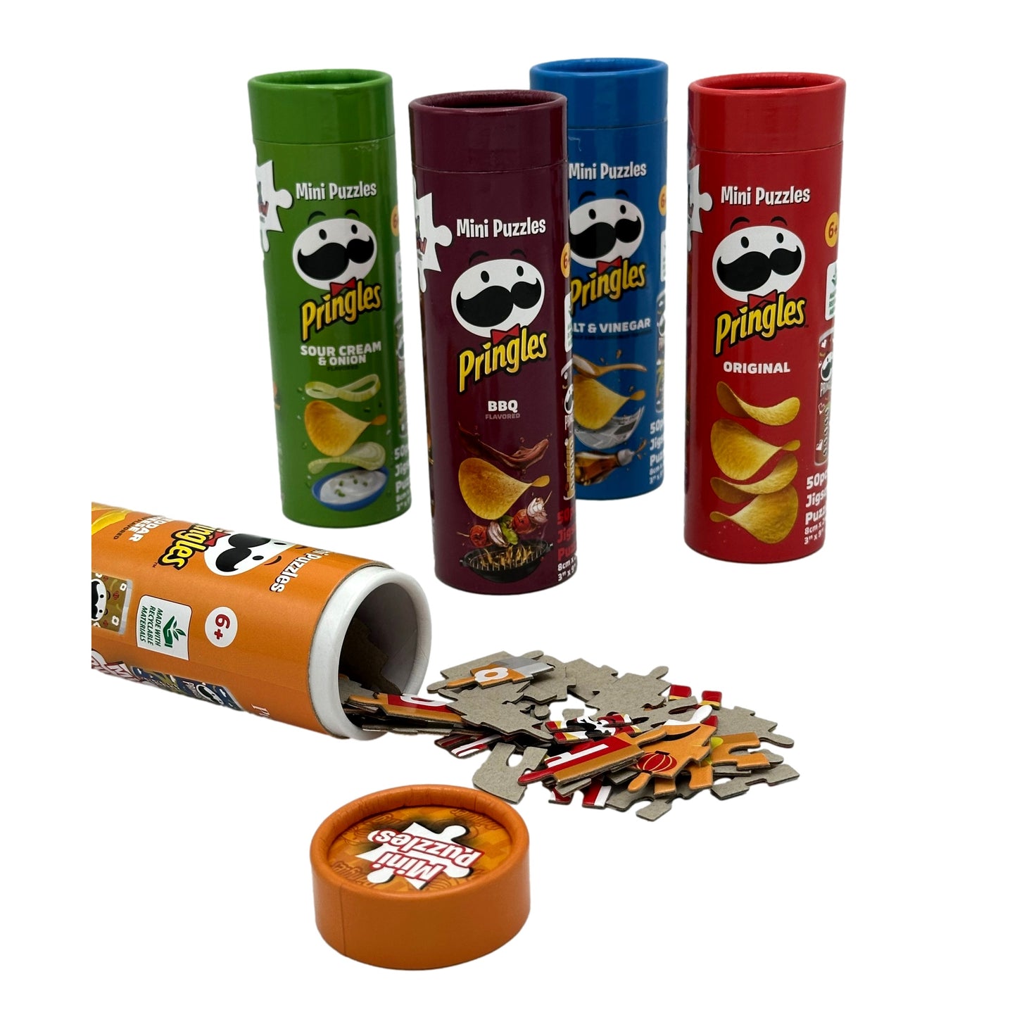Assorted Pringles mini puzzles in cylindrical containers, with one container open and puzzle pieces scattered around.