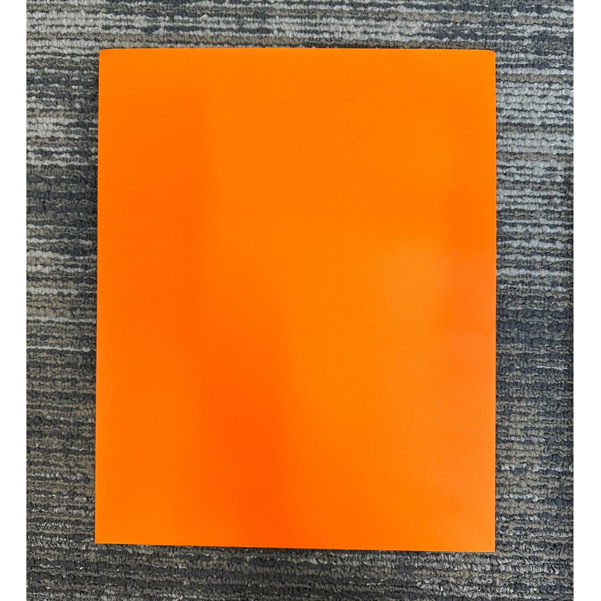 Square, bright orange material on gray textured carpet.