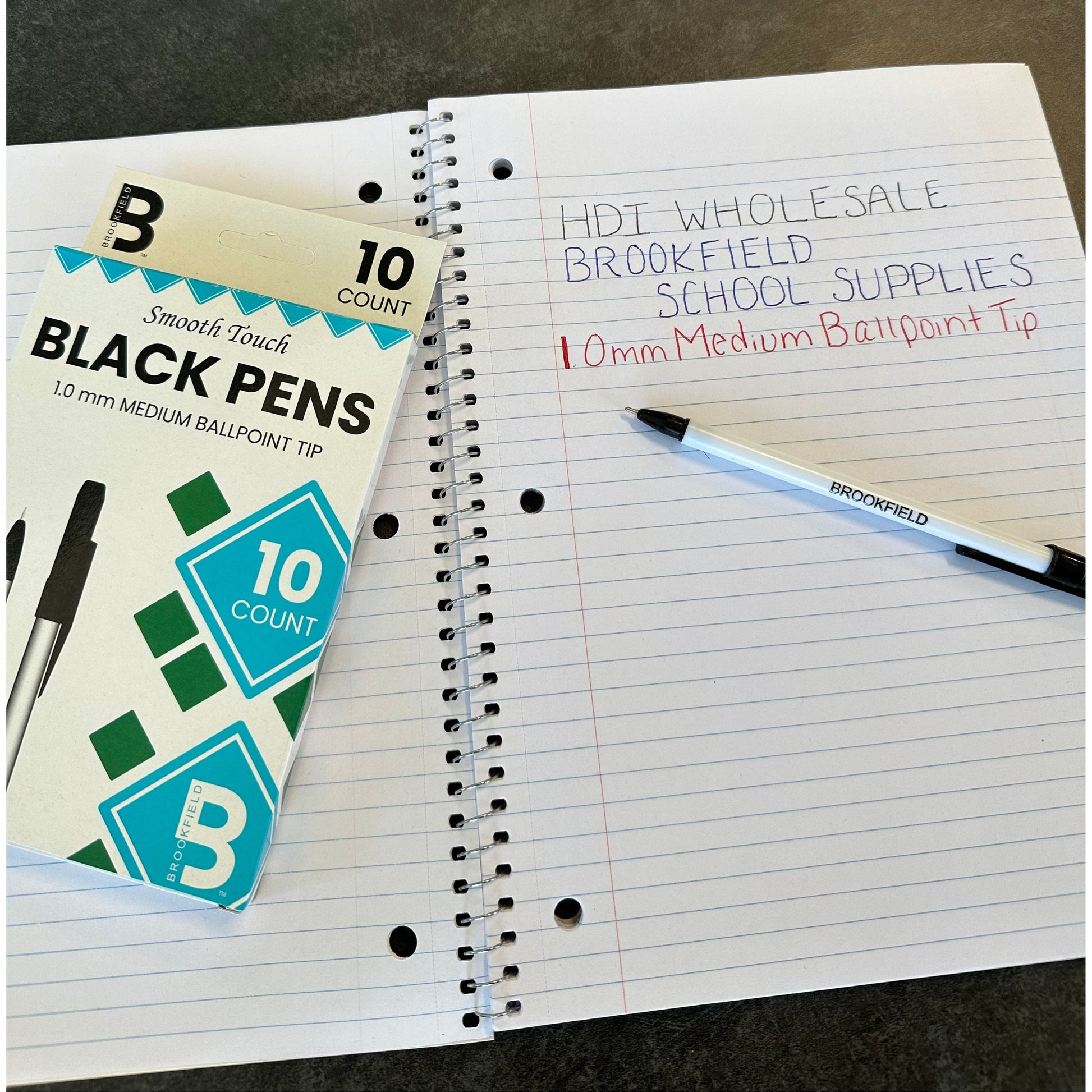 Close-up product shot of Brookfield black pens with a notebook on a dark surface.