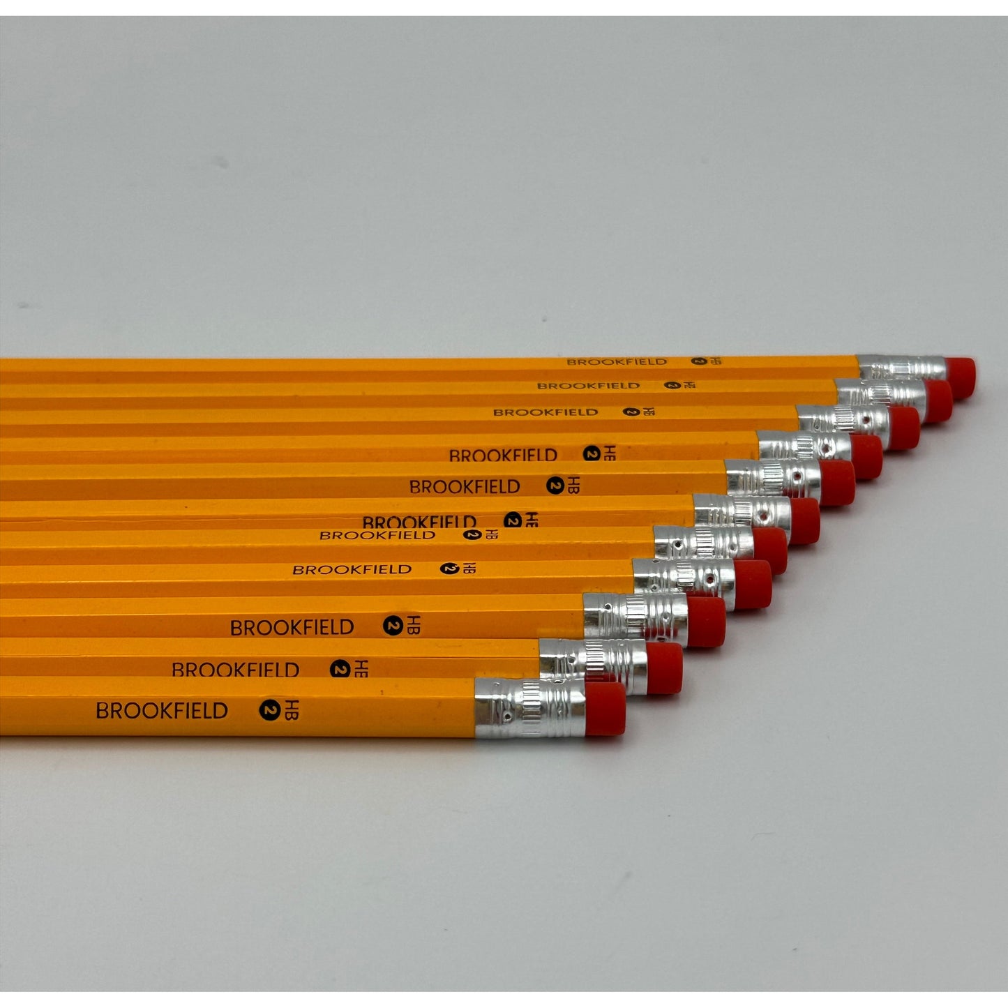 A stack of yellow Brookfield brand pencils with red erasers and silver ferrules.