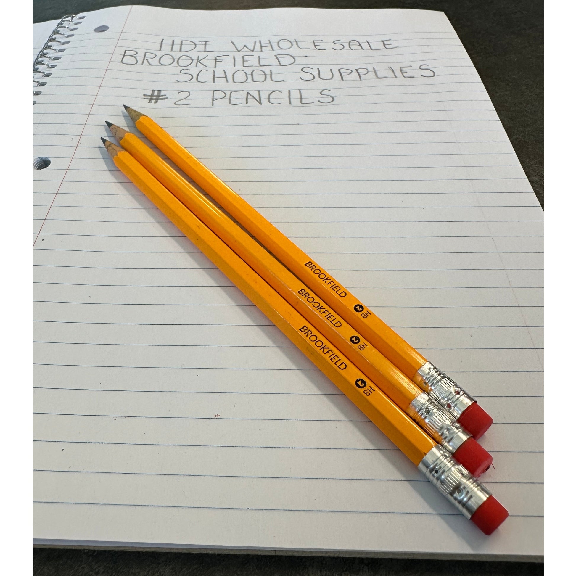 Three yellow Brookfield #2 pencils with red erasers on lined paper.