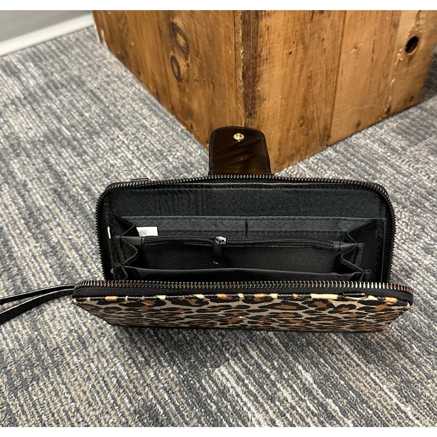 Leopard print wallet with a black interior and wrist strap.