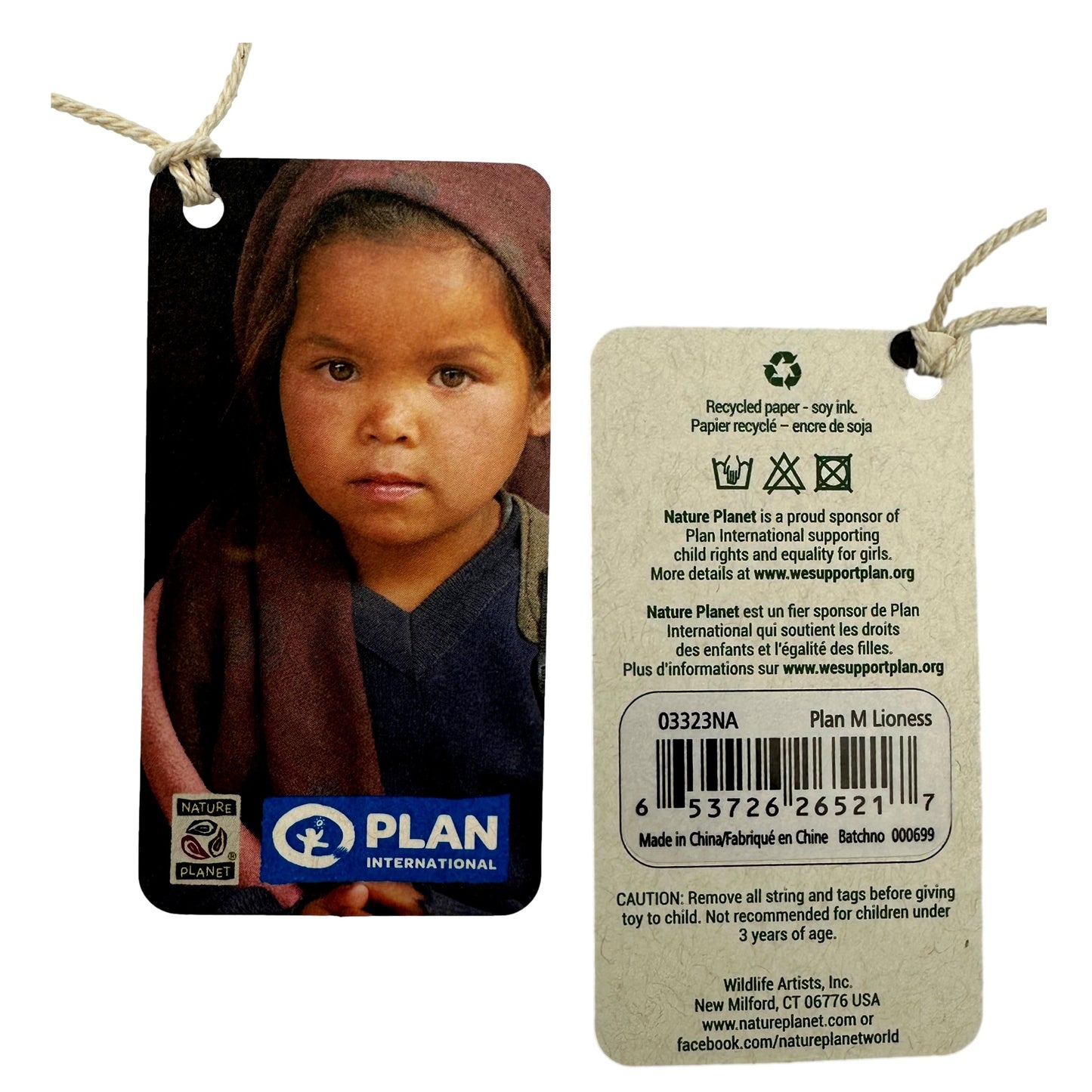 Two product tags attached with knotted strings. One features a portrait of a young girl in a maroon scarf. The other tag has the Nature Planet logo and product information, including a warning.