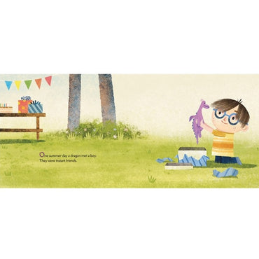 A book illustration featuring a boy with glasses holding a purple dragon toy while sitting next to an open gift box, set in a grassy outdoor scene with a table, gifts, and festive banners in the background.