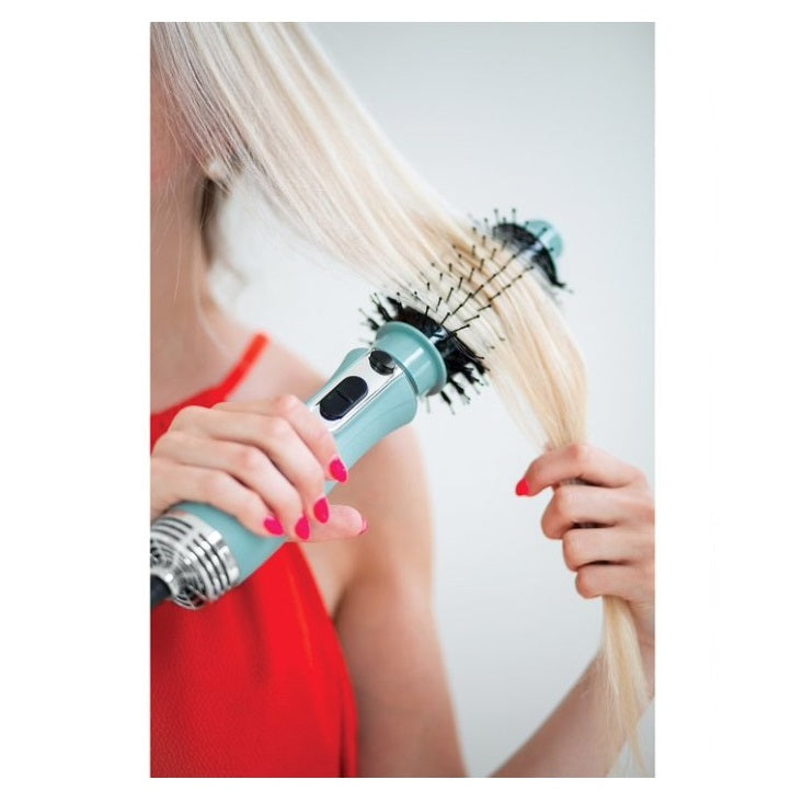 Blonde woman holding a light-blue hot air brush to style her hair; she is wearing a red top.