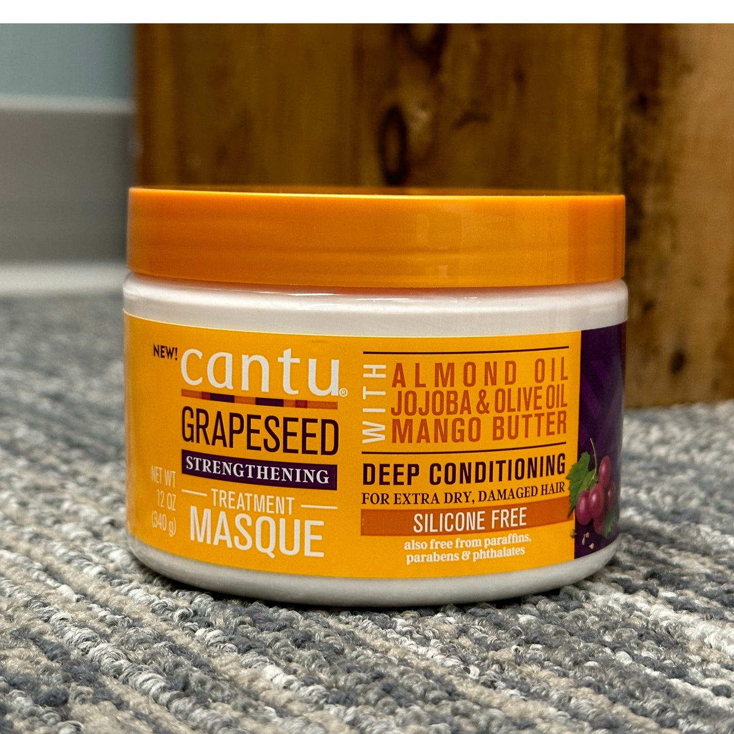 A tub of Cantu Grapeseed Strengthening Masque on a gray, textured surface.