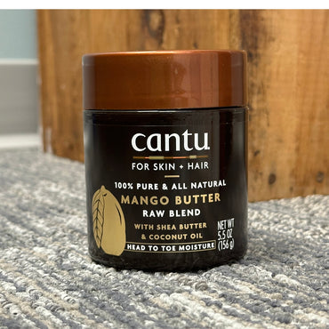 A brown and black jar of Cantu Mango Butter.