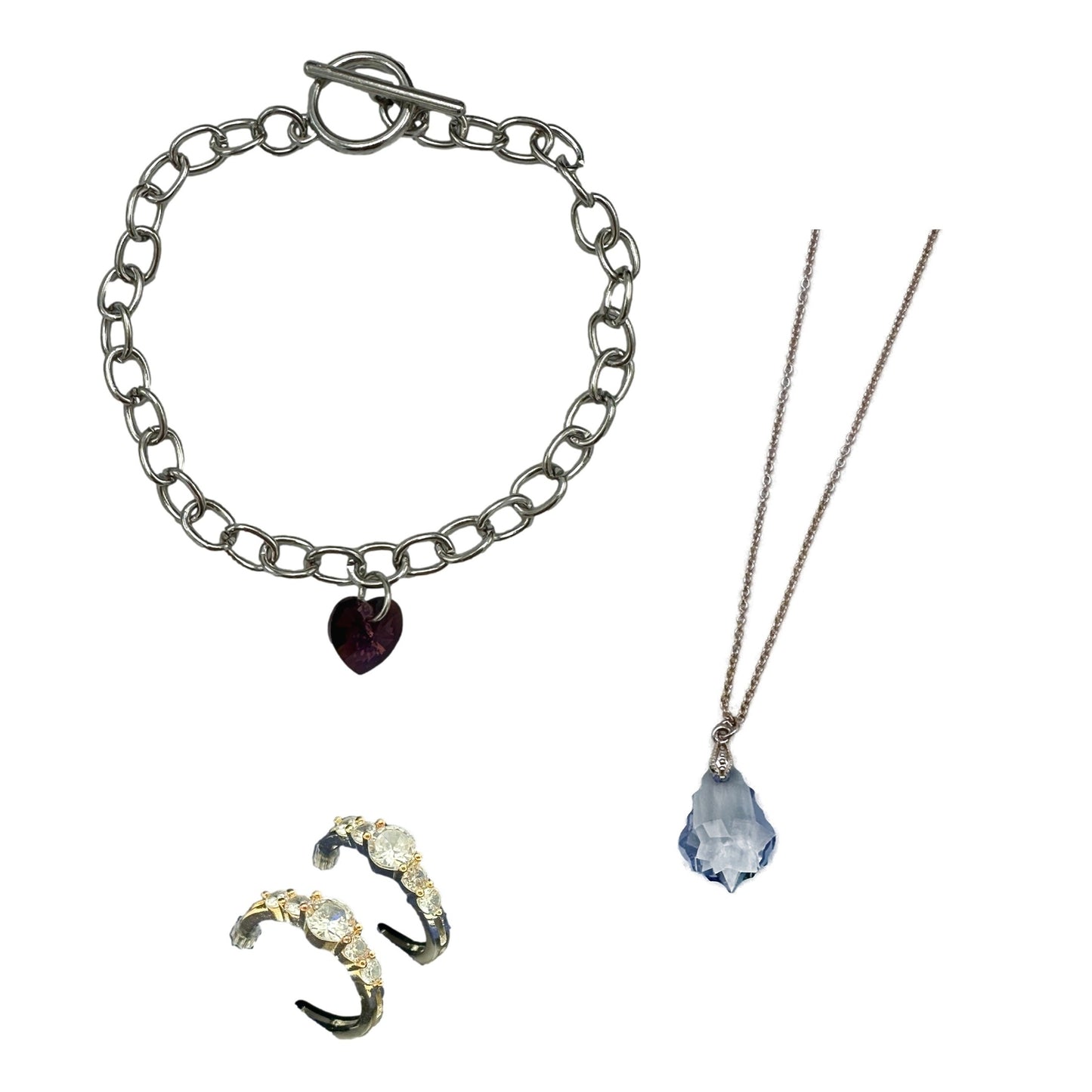 Silver chain bracelet with purple heart pendant, silver necklace with blue crystal pendant, and gold and black gemstone earrings.