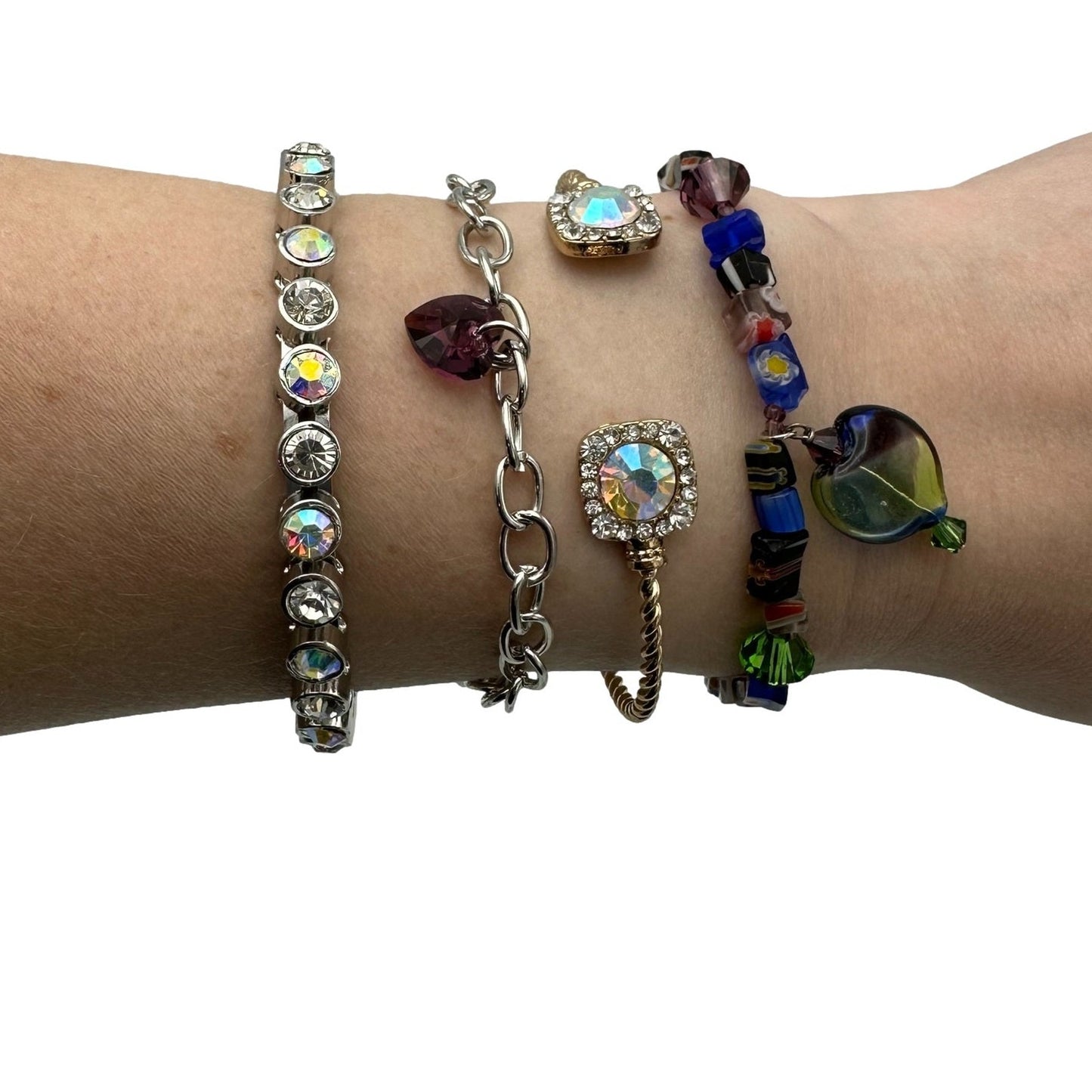 Close-up of a wrist adorned with four bracelets featuring colorful beads, stones, and charms.