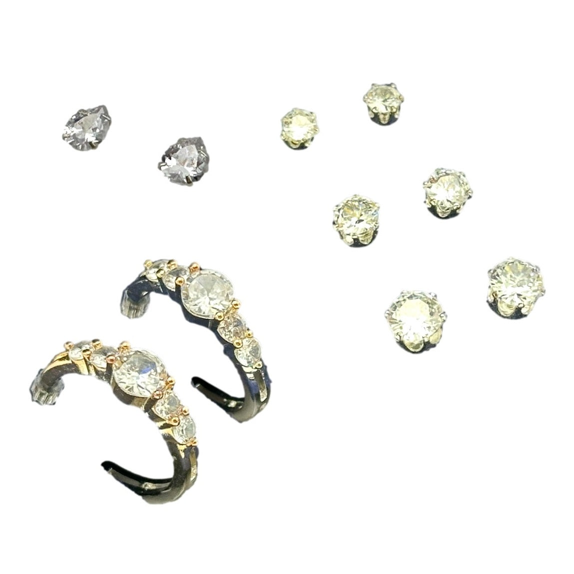 An array of jewelry, including ear cuffs with golden bands and sparkling gemstones, and several loose, round-cut gemstones.