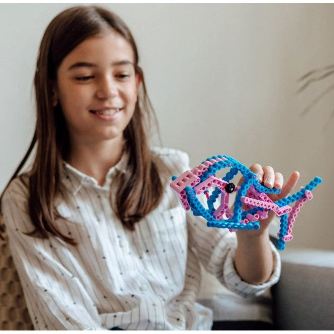 Smiling girl holding a blue and pink building block fish.