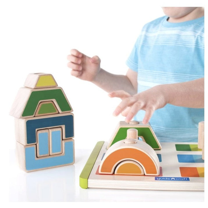 Child playing with colorful wooden block toys on a white table.