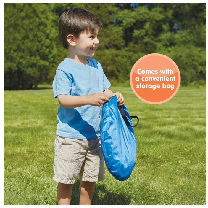 Child holding a blue storage bag outdoors with greenery in the background