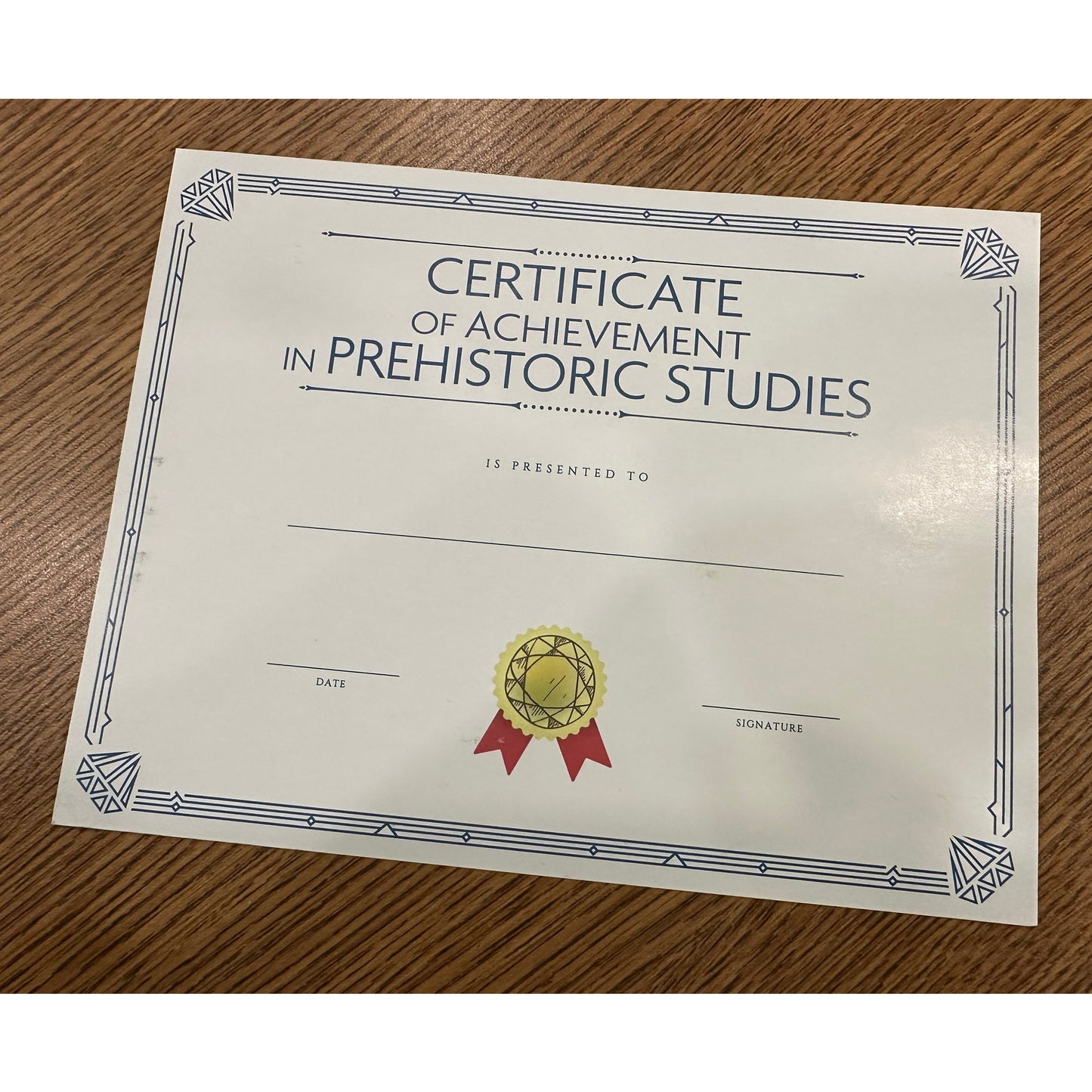 A certificate of achievement in prehistoric studies on a wooden surface.