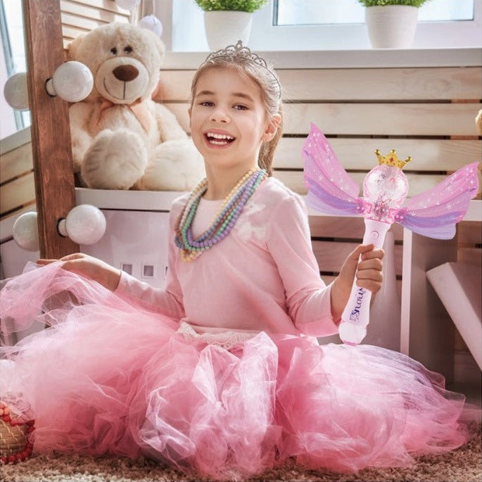A young girl in a pink tutu and tiara holds a fairy wand.