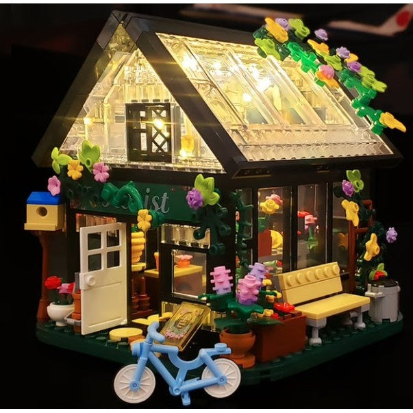 Lego florist shop with lights, flowers, bench, bicycle, and birdhouse.
