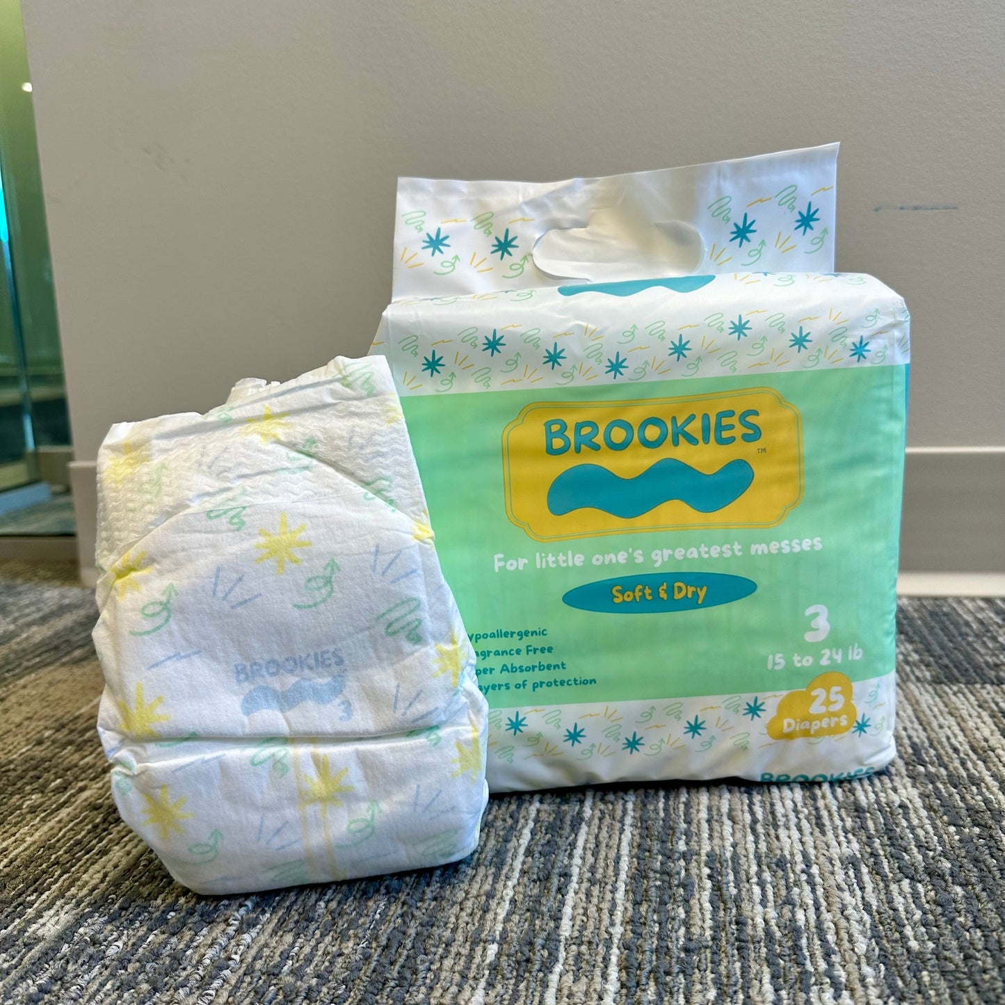 A package and a single "Brookies" brand diaper on a neutral gray rug.