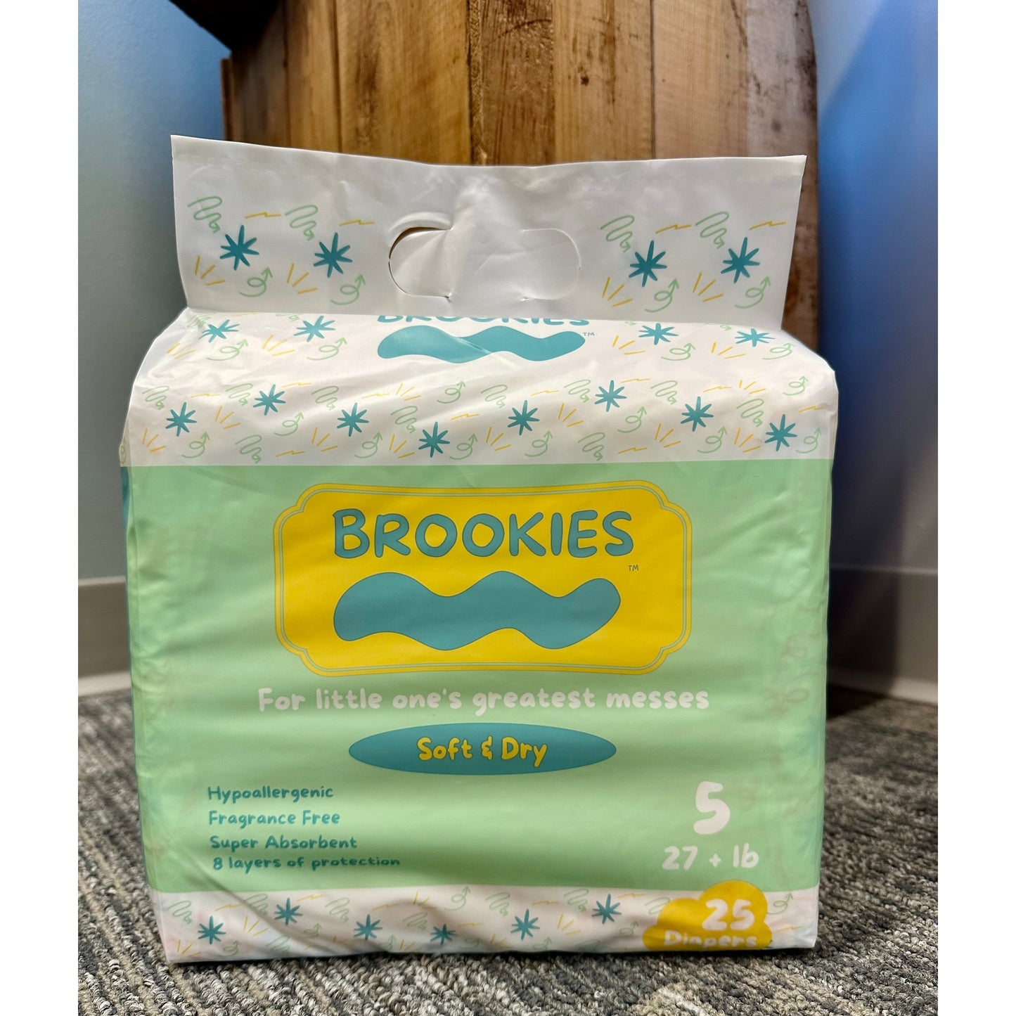 A package of Brookies brand diapers on a carpeted floor.