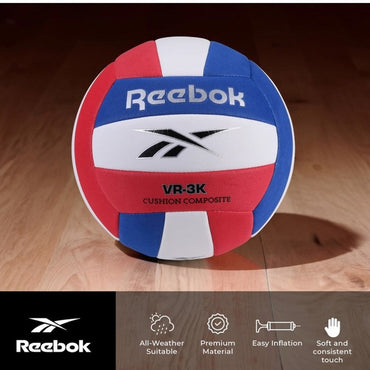 A red, white, and blue Reebok volleyball on a wooden floor.