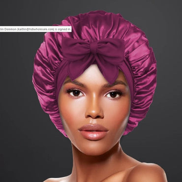 Close-up of a woman wearing a shiny magenta satin hair bonnet with a large bow.