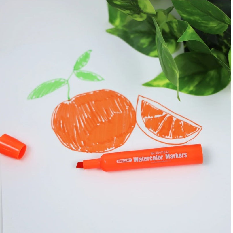 An orange-colored marker is placed on white paper with orange and green drawings of an orange fruit and slice of orange. A green plant is in the background.