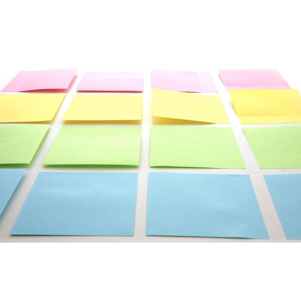 A grid of pink, yellow, green, and blue sticky notes on a white surface.
