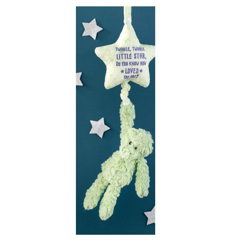 A hanging baby mobile toy with a plush green bear dangling from a plush yellow star against a dark blue background with silver stars.