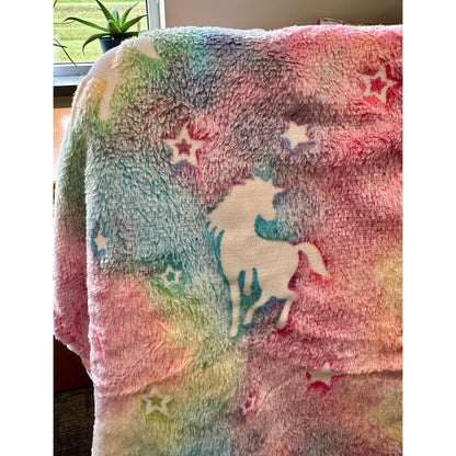 Fuzzy rainbow-colored blanket with a unicorn and stars.