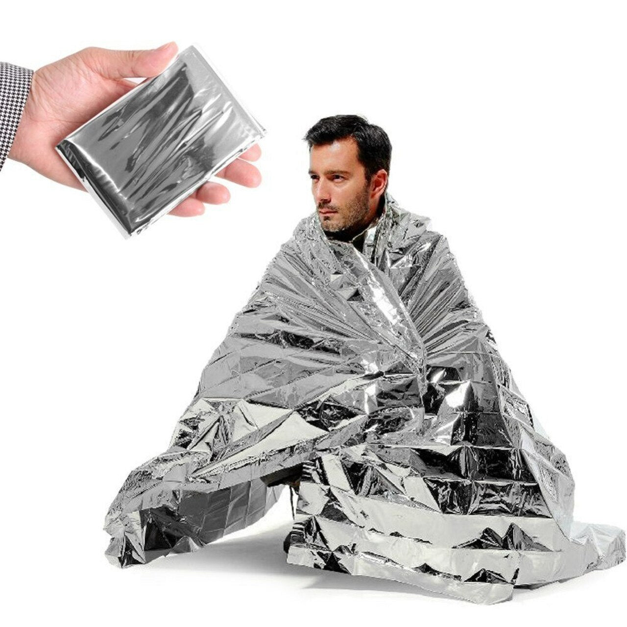 A man wrapped in a silver emergency blanket, with a packaged blanket in hand.
