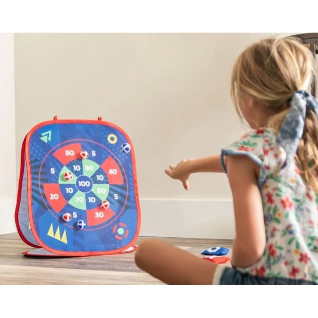 A child throwing a beanbag at a beanbag dartboard.