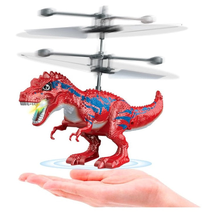 Toy dinosaur with propellers hovers over a hand. The dinosaur is red with blue markings and has a light shining from its mouth.
