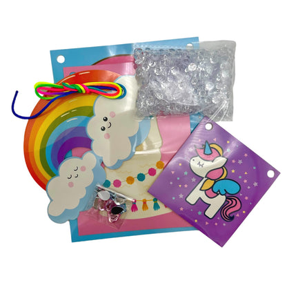 An assortment of craft supplies, including a rainbow cutout, cloud shapes, gems, colorful string, and a unicorn decoration.
