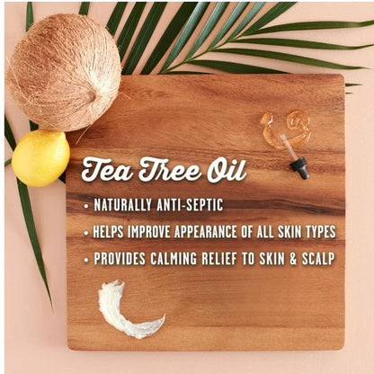 Product shot for Tea Tree Oil on a wooden board with coconut, lemon, palm leaf, oil droplet, and lotion sample.