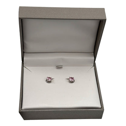 Pink stud earrings in a gray box.
