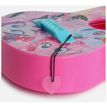 Close-up of a pink My Little Pony toy guitar with a transparent heart charm hanging from a black cord.

