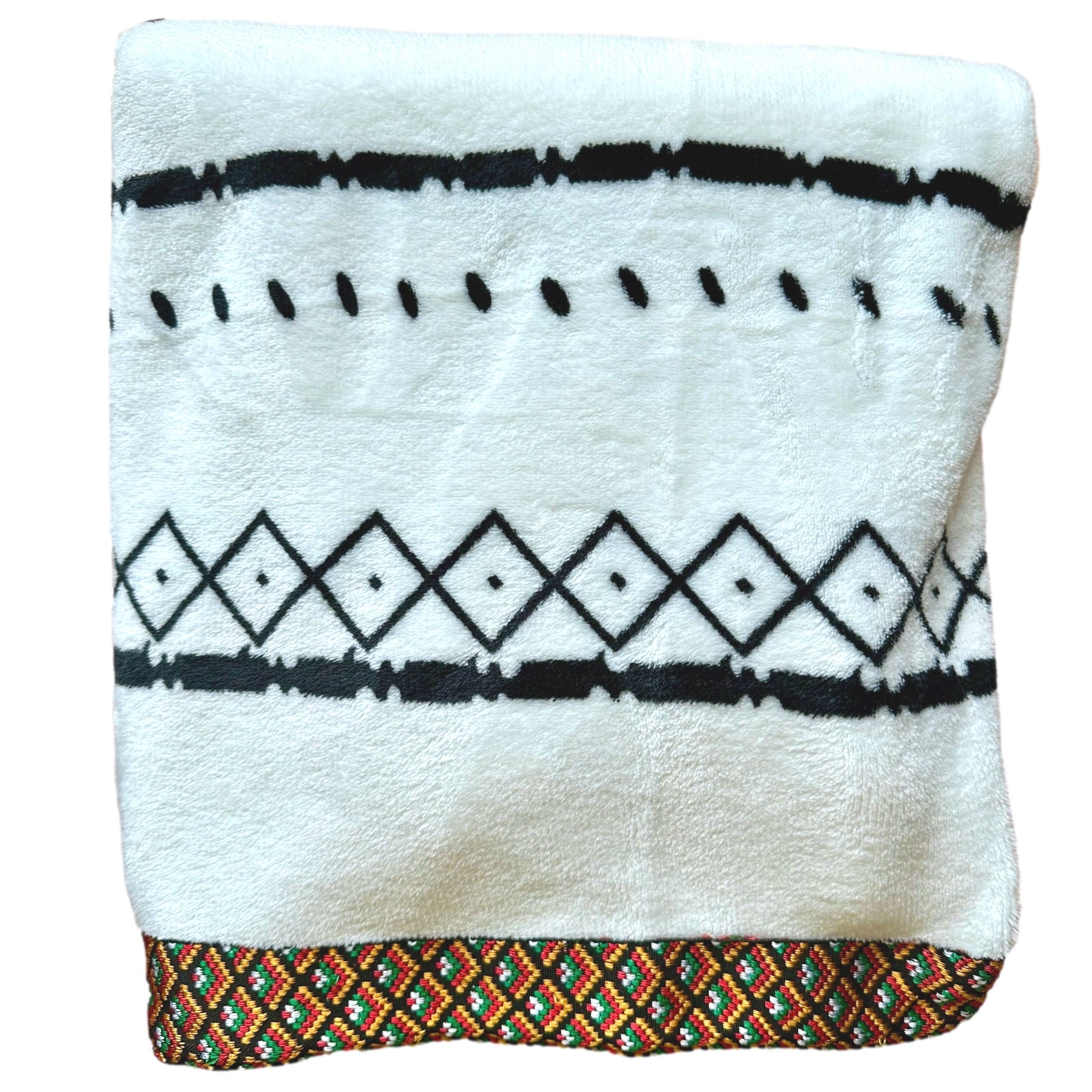 White fuzzy blanket with black patterns and a colorful, patterned border.
