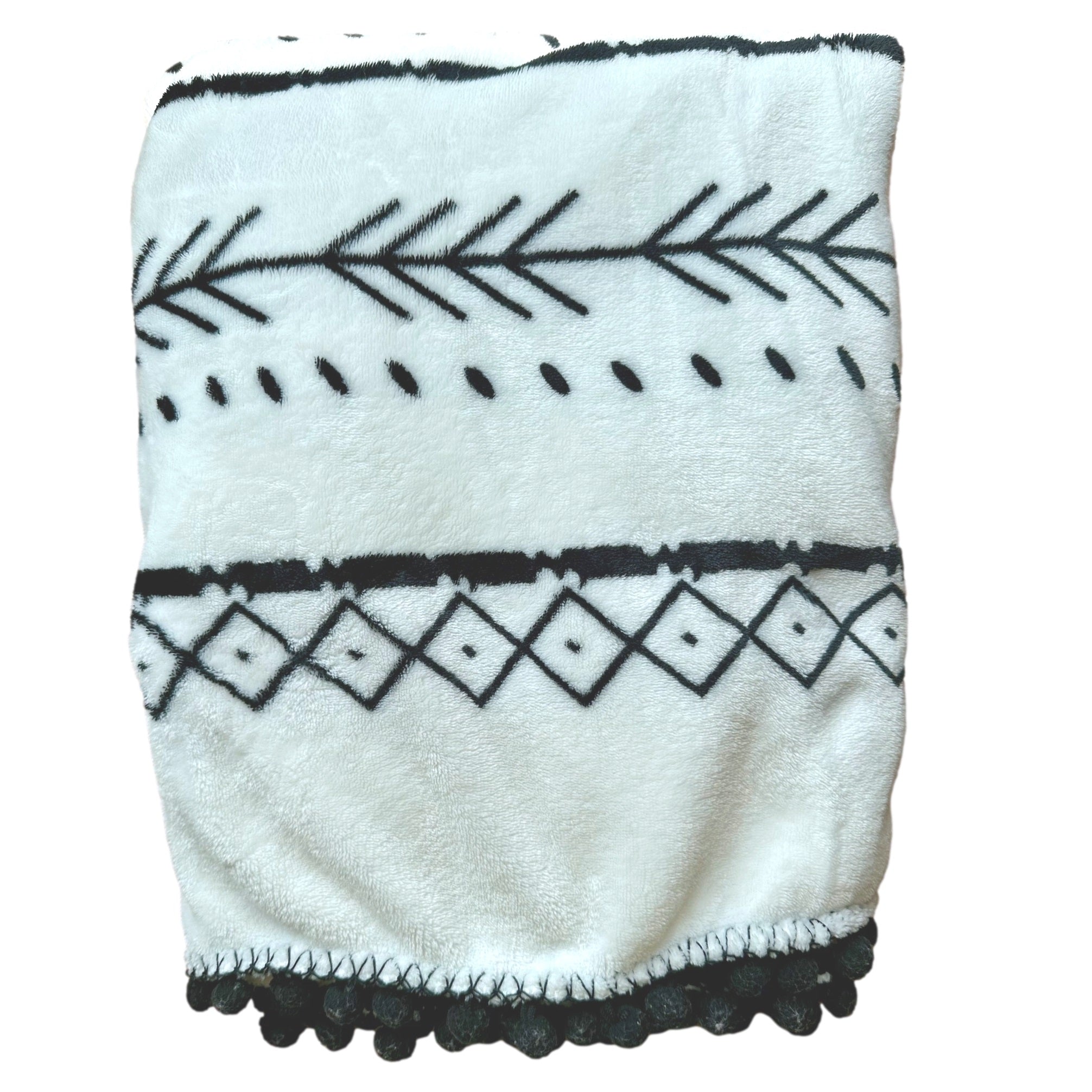 White blanket with black geometric patterns and pom-pom fringe.

