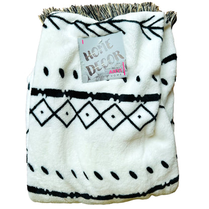 White plush blanket with black geometric pattern and fringe.