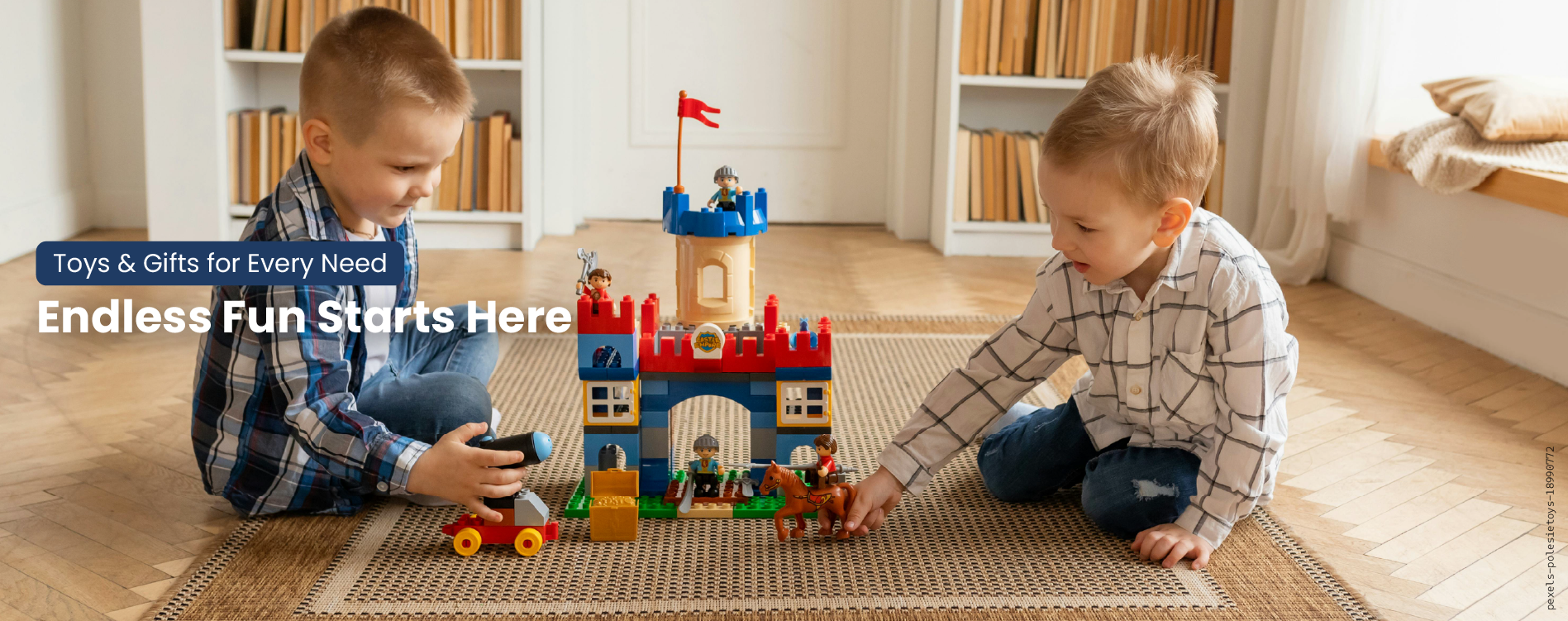 Two children playing with a toy castle on a rug in a room with books and a flag.